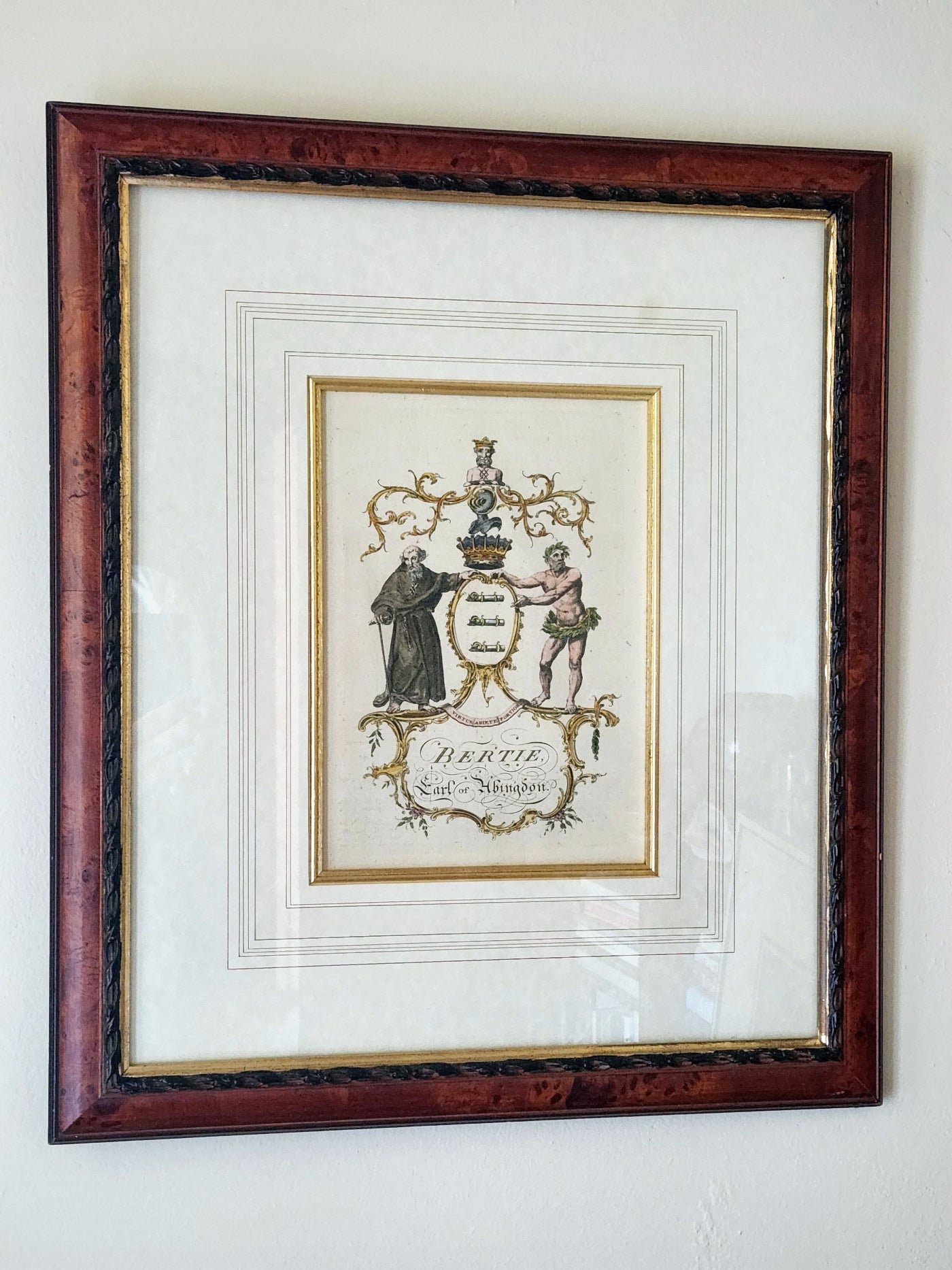 Framed artwork with a coat of arms on a white wall